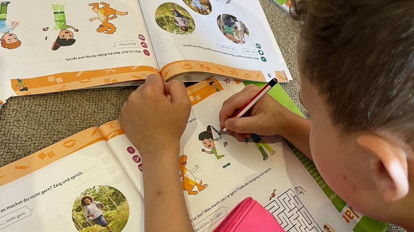 A boy completing a drawing in a German text book.