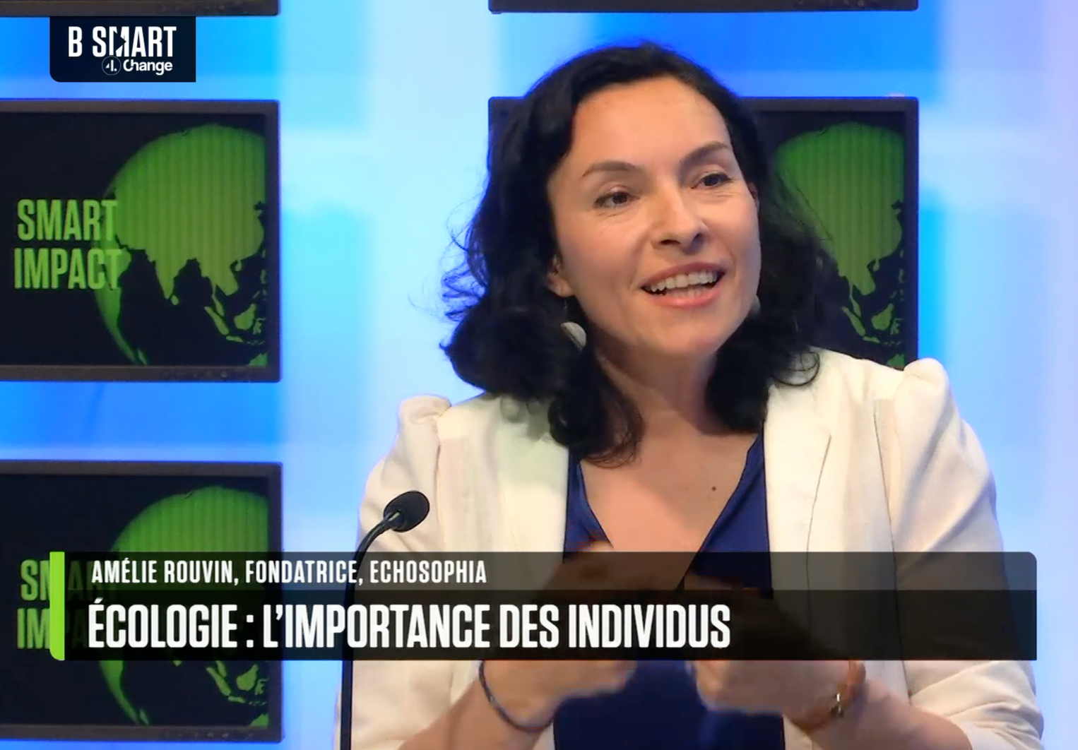 photo d'Amélie Rouvin en conférence, micro, pull vert, fond noir