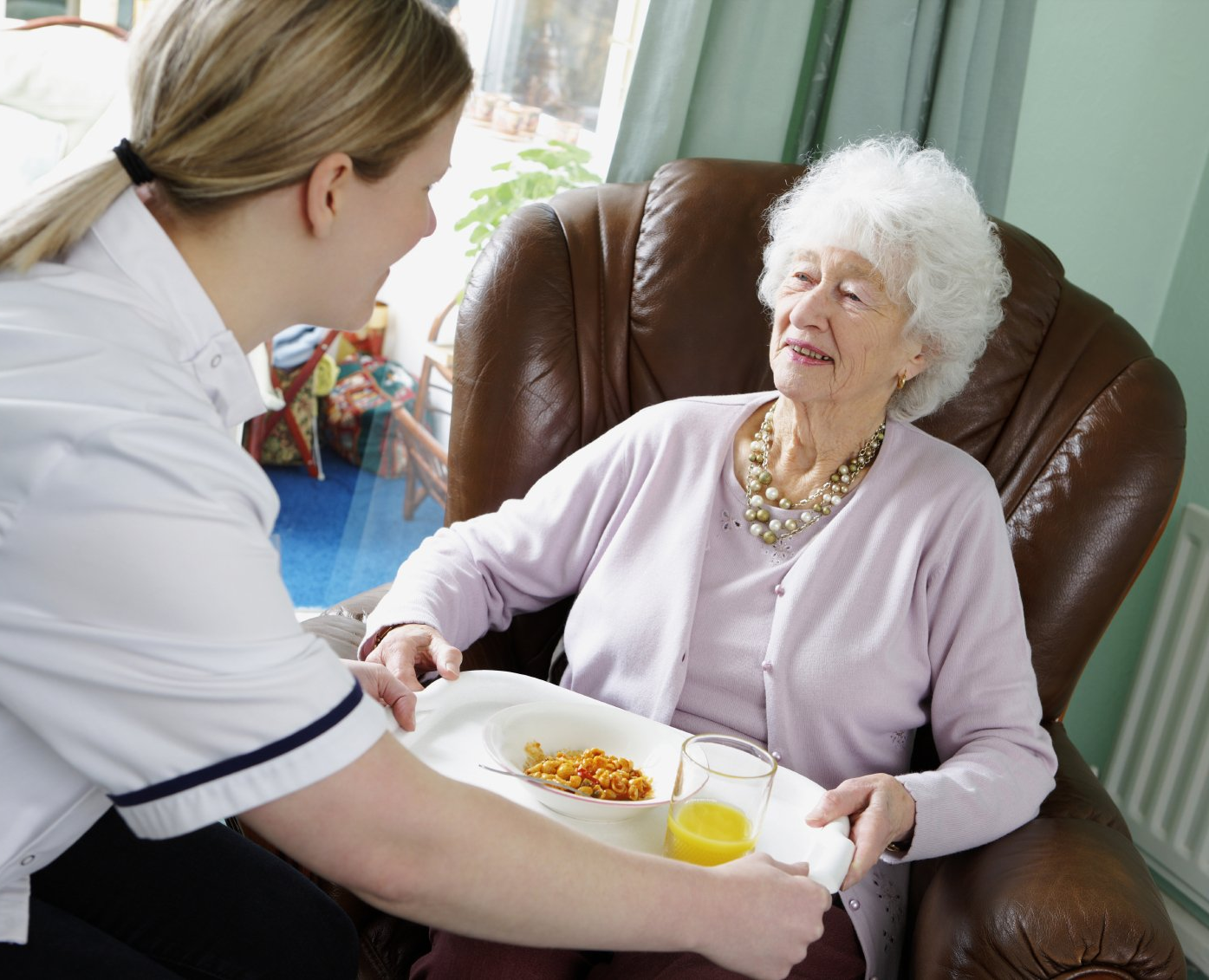 Die Betreuerin bringt der Oma ihr essen