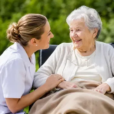Oma sitzt im Rollstuhl und die Betreurin spricht mit ihr