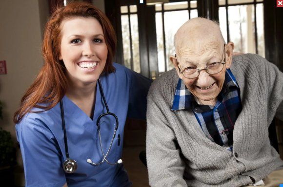 Opa (Inkontinent) und Pflegerin lachen zusammen