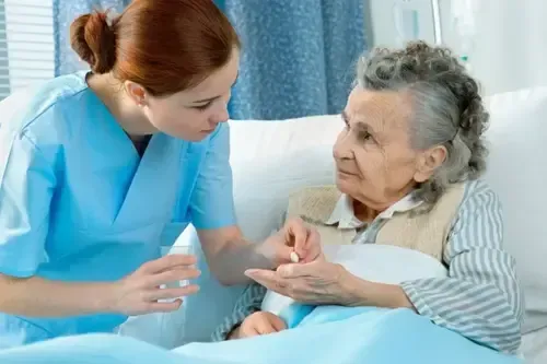 Oma sitzt und schaut freundlich auf die Pflegerin auf Oma sitzt und schaut freundlich auf die Pflegerin auf