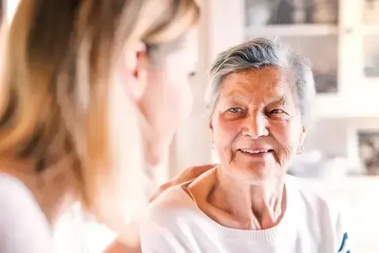 Die Pflegerin blickt zur Oma und Sie lächelt zurück