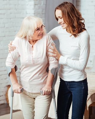 Amyotrophe Lateralsklerose (ALS - Patient) geht mit Pflegerin mit Gehstöcke