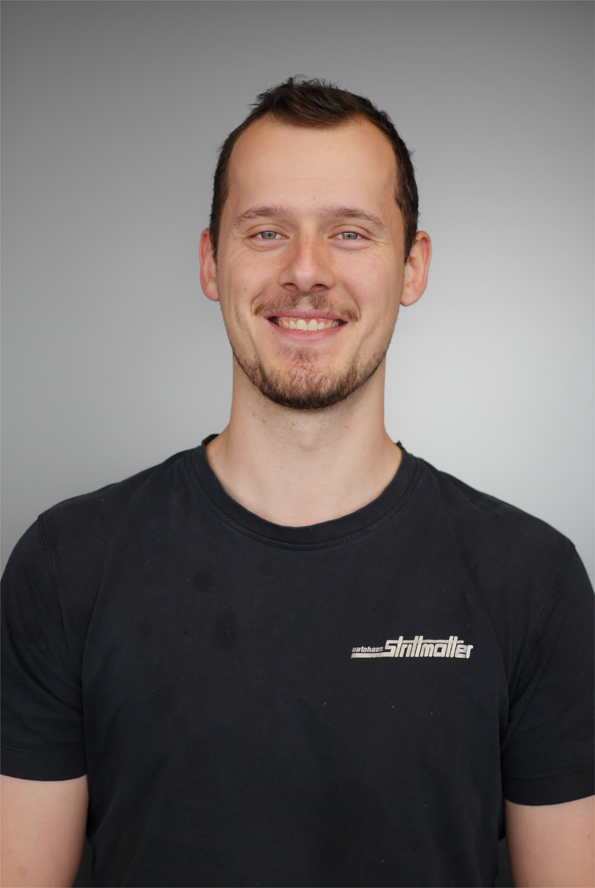 Mann mit schwarzen Tshirt und blauer Latzhose