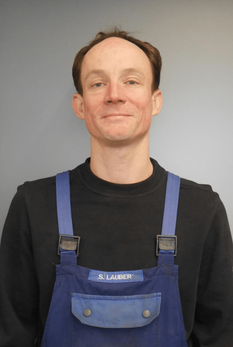 Mann mit schwarzen Tshirt und blauer Latzhose