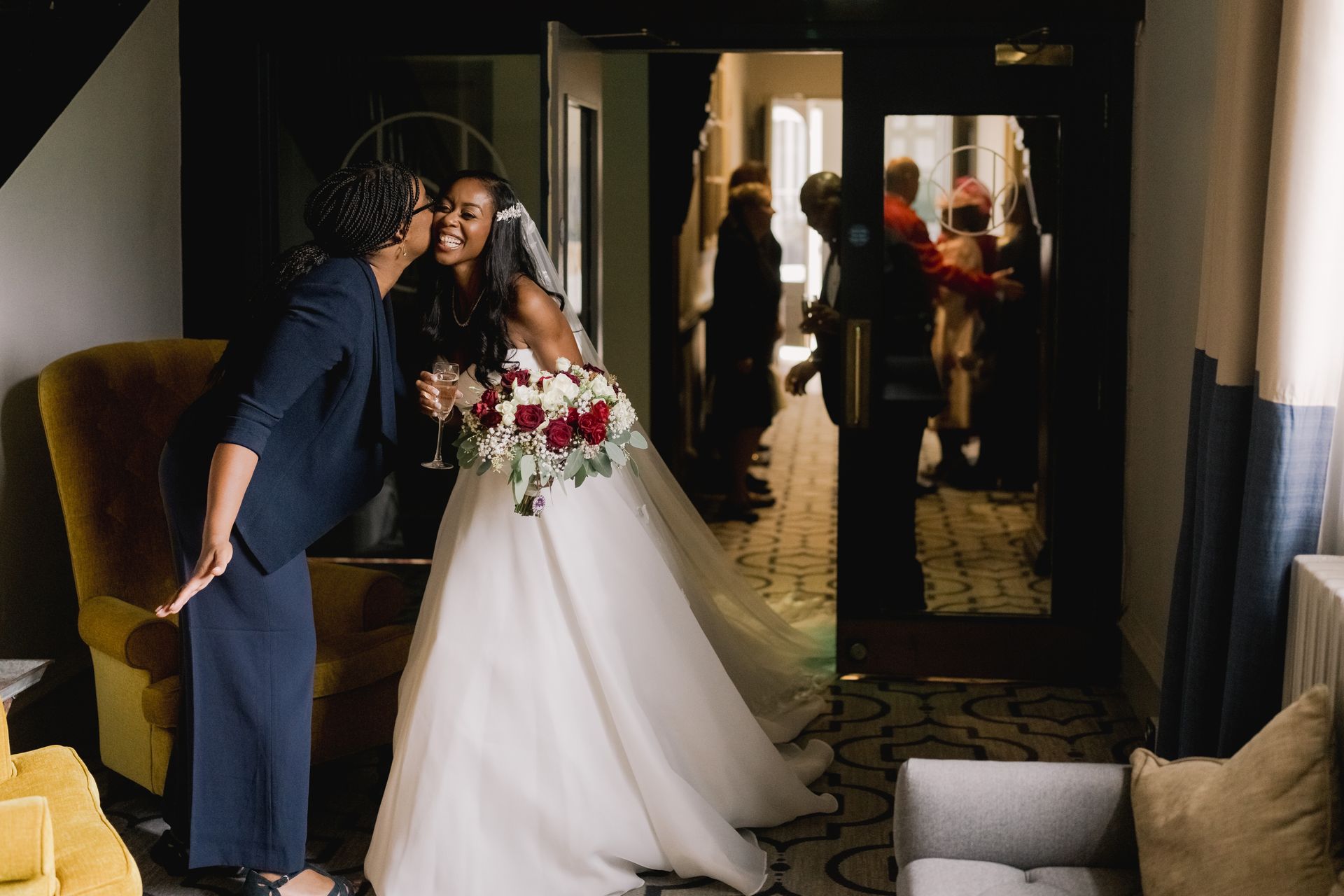 Black bride with her bouquet greeting wedding planner with a kiss
