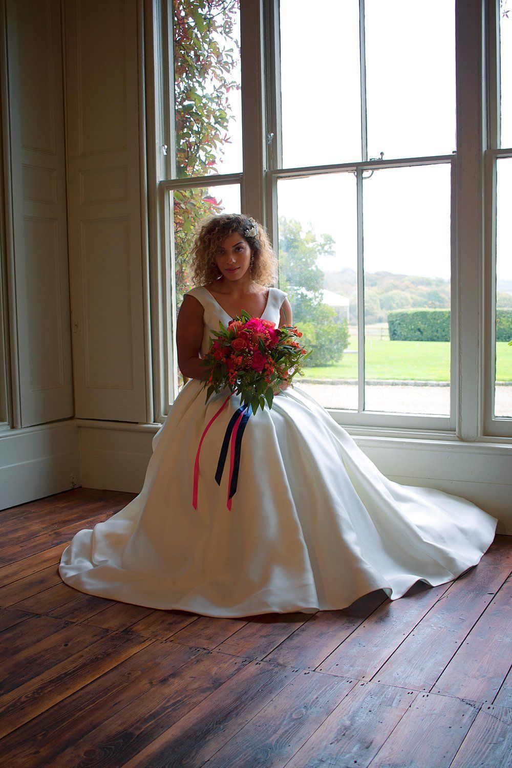Bride seated by window holding bouquet Nurstead Court Kent