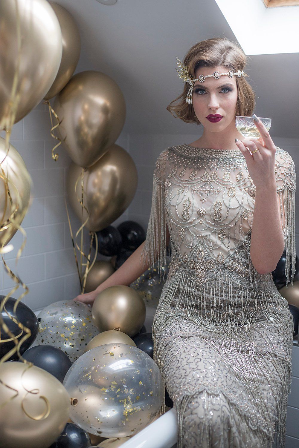 Great Gatsby Bride seating by the bathroom with champagne and gold balloons