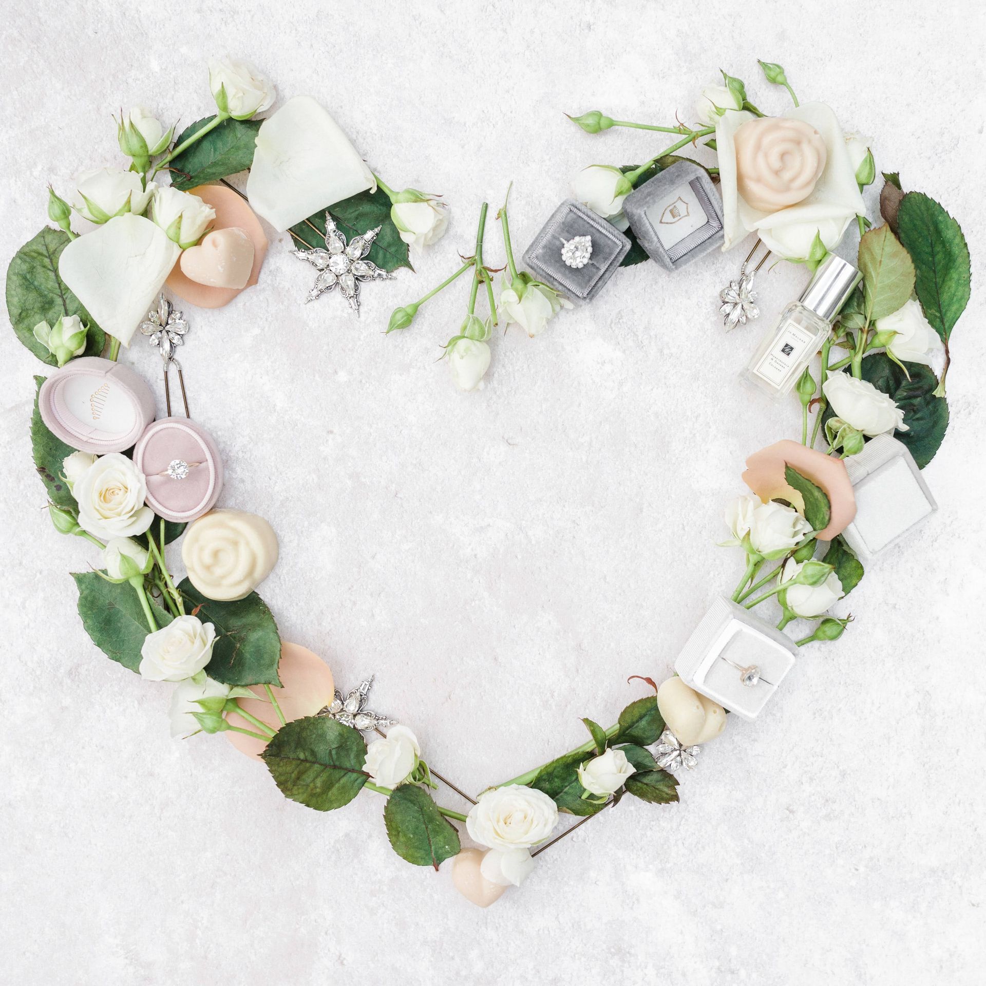 Heart shape made out of perfume bottles, flowers and wedding ring boxes