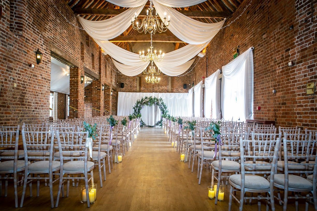 Planning a fusion wedding Ghanaian-Italian Wedding in a London Dry Hire venue ceremony set up with a floral arch with eucalyptus and purple flowers