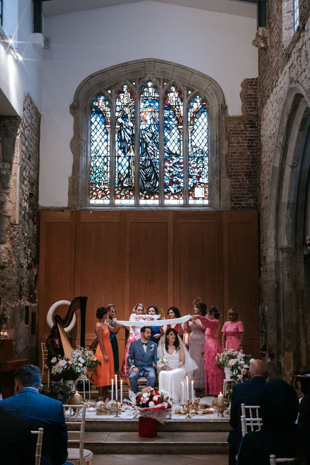 Persian wedding ceremony bride and groom seated at Sofreh aghd with stained glass window in the background