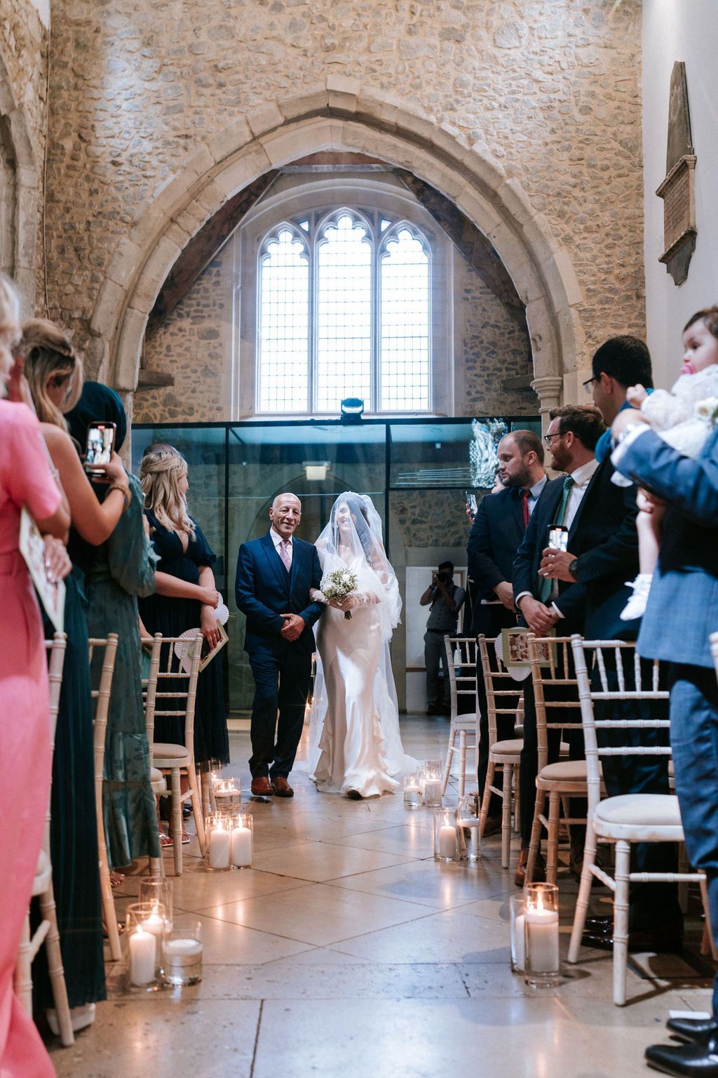 White bride in white dress walking down the aisle with her father in dark suit