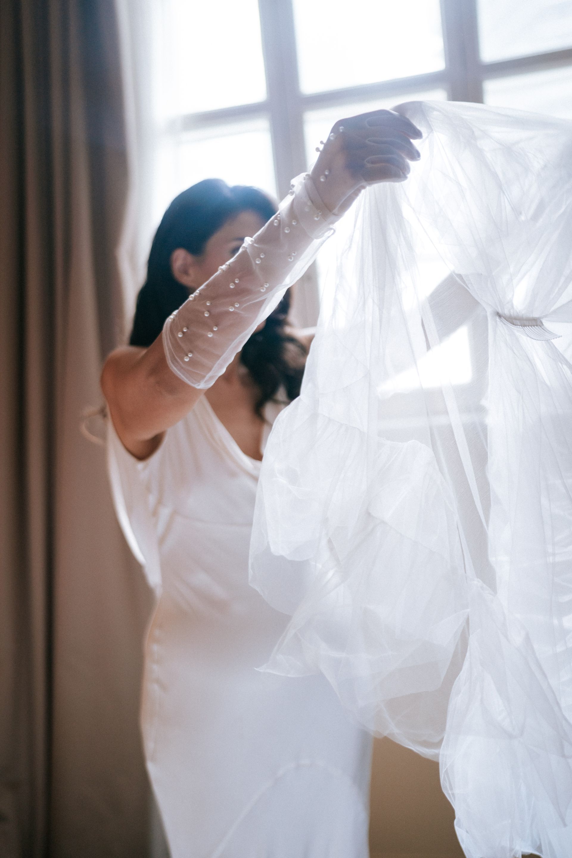 Bride in a white dress looking at her veil