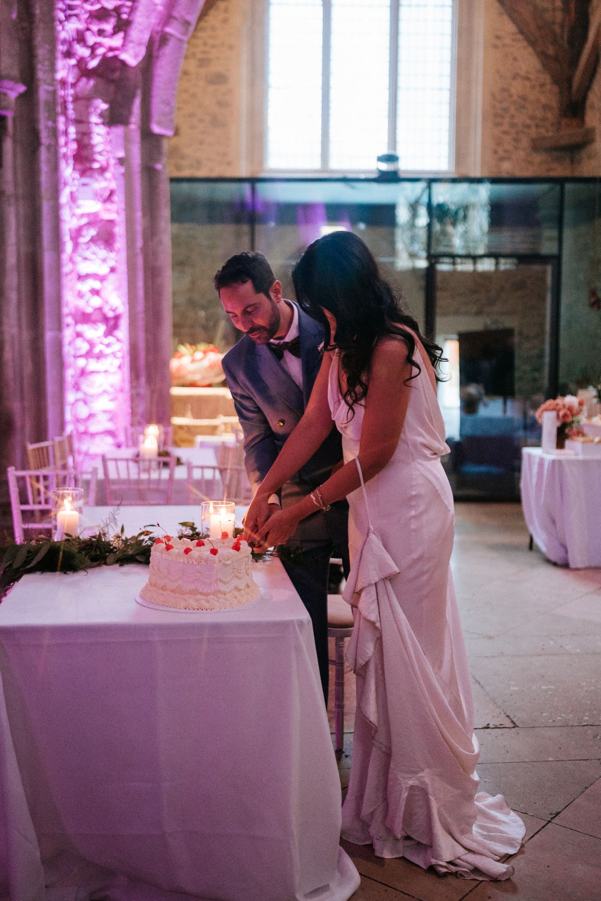 Bride and groom standing and cutting wedding cake