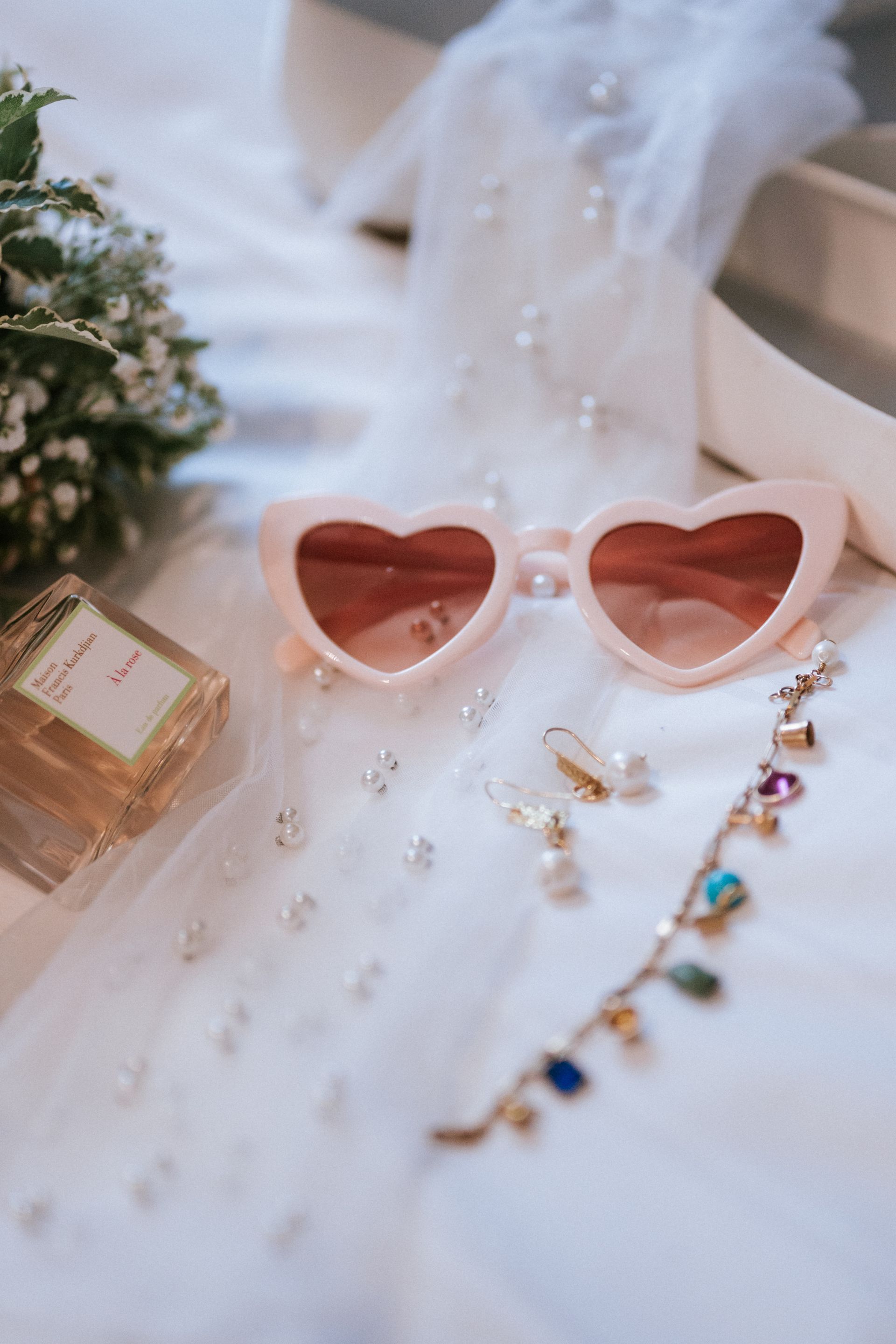 Bride flat lay with pink heart glasses and perfume