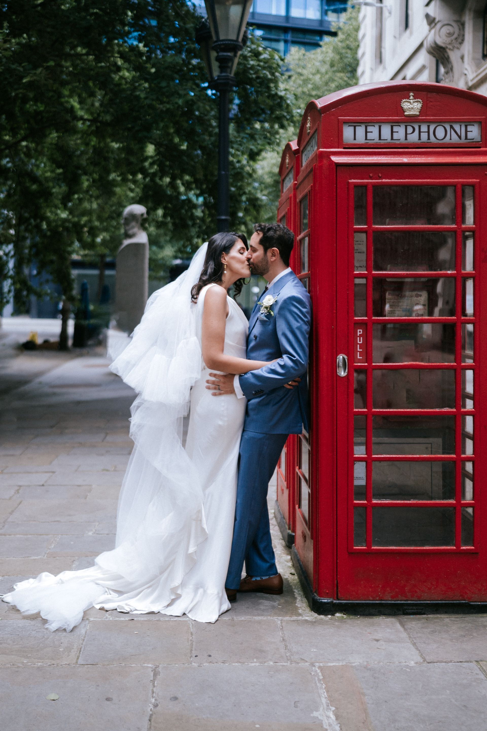 Bride and Groom kissing whilst leaning against red London phone booth