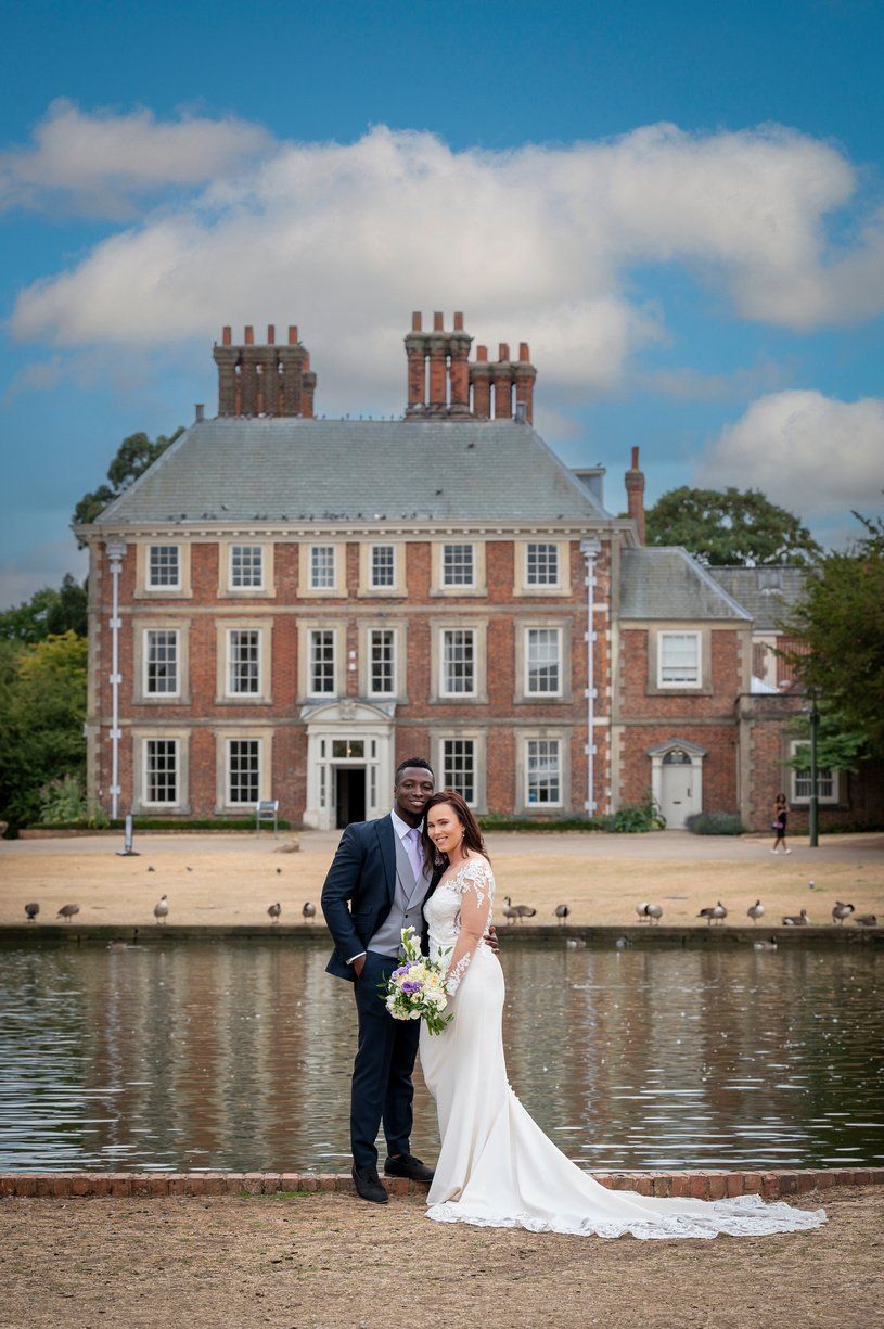 Black groom and white bride standing outside Forty Hall Enfield