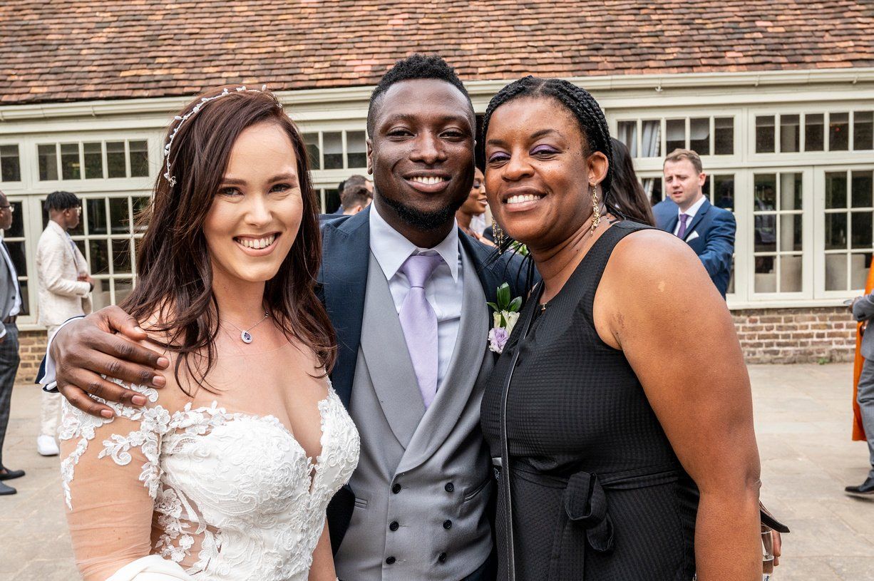 Black groom white bride looking at camera and smiling with wedding planner