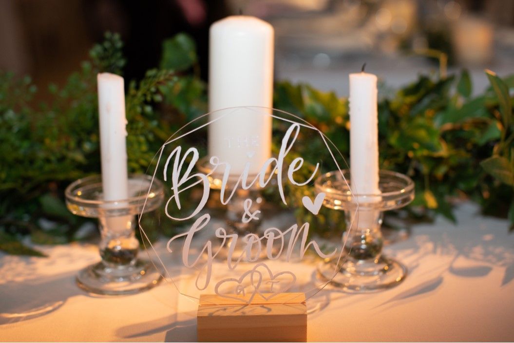 bride and groom acrylic sign with white writing and 3 candles