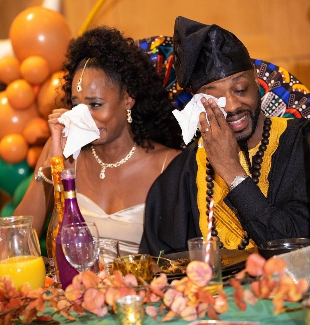 black bride and groom seated both crying and wiping eyes with tissues