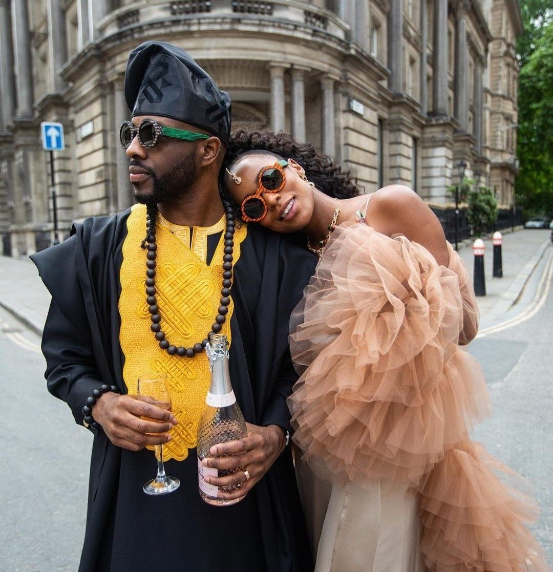 Black bride leaning on black groom wearing black agbada standing outside in the City of London