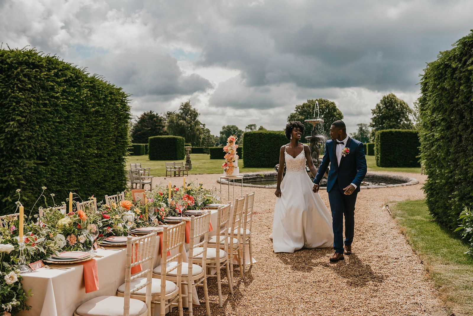 Black bride and groom holding hands walking towards their garden wedding reception table