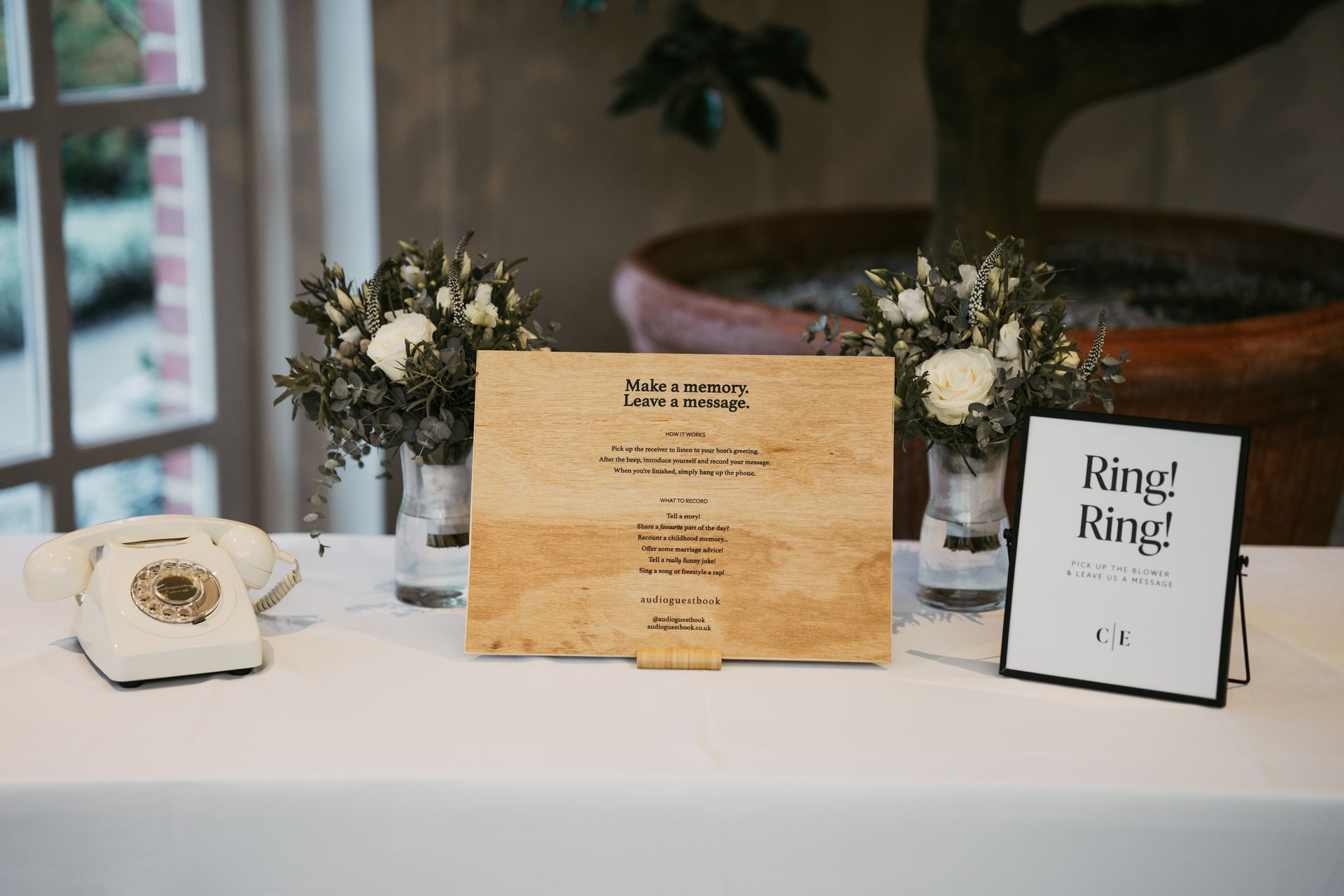 Audio guest book sign and white phone on a table and surrounded by flowers