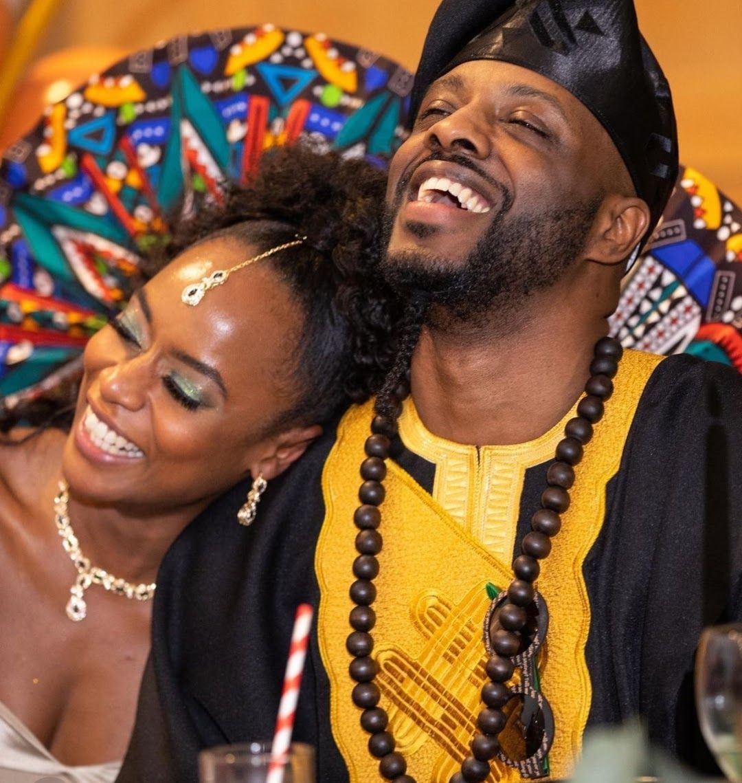 Multicultural wedding couple smiling whilst sitting at the reception table with colourful decor