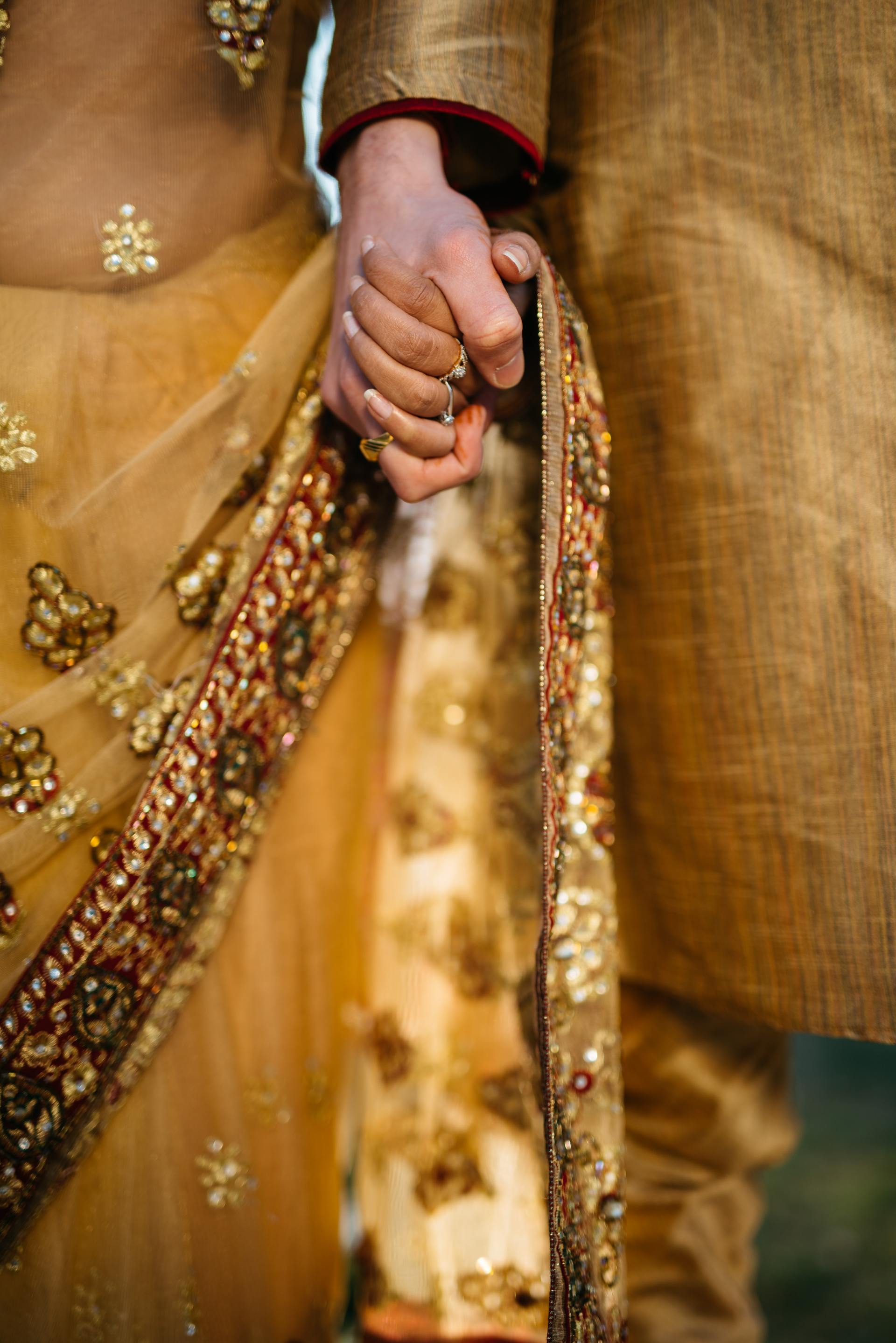 Asian wedding bride and groom in mustard yellow holding hands