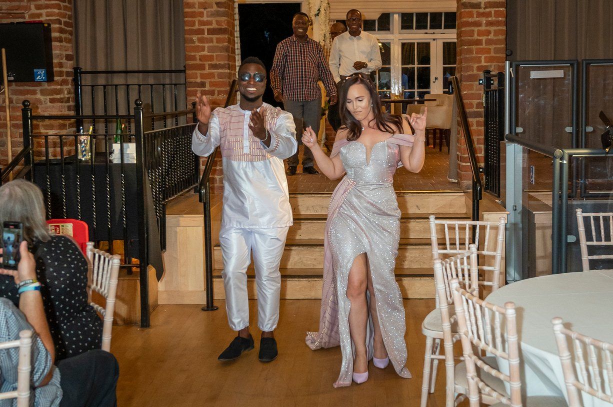 Black groom white bride dancing in wearing traditional Ghanaian outfits fusion wedding dancing