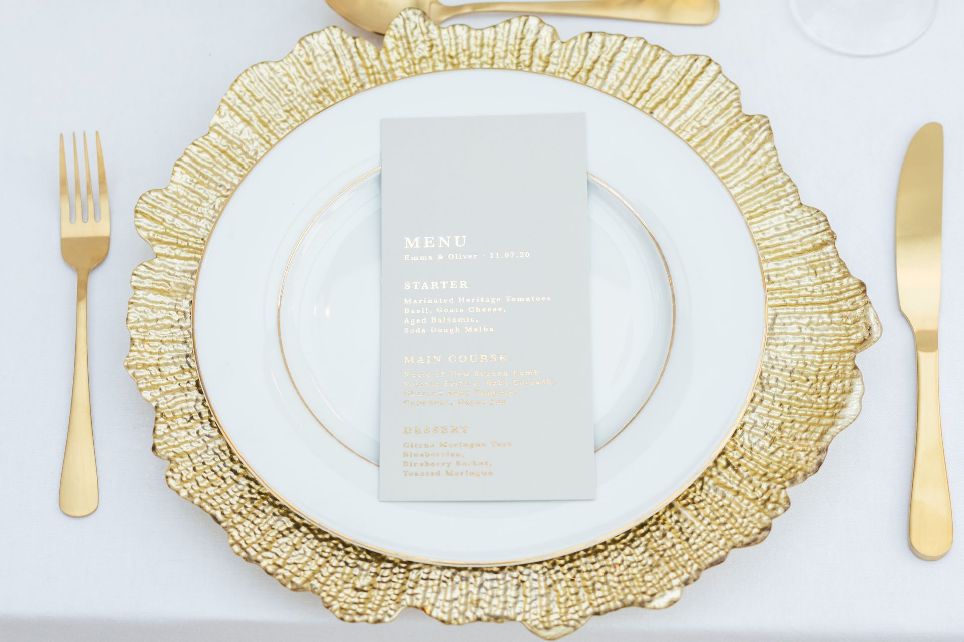 Gold reef charger plate with white dinner plate and grey menu with gold letteringon top