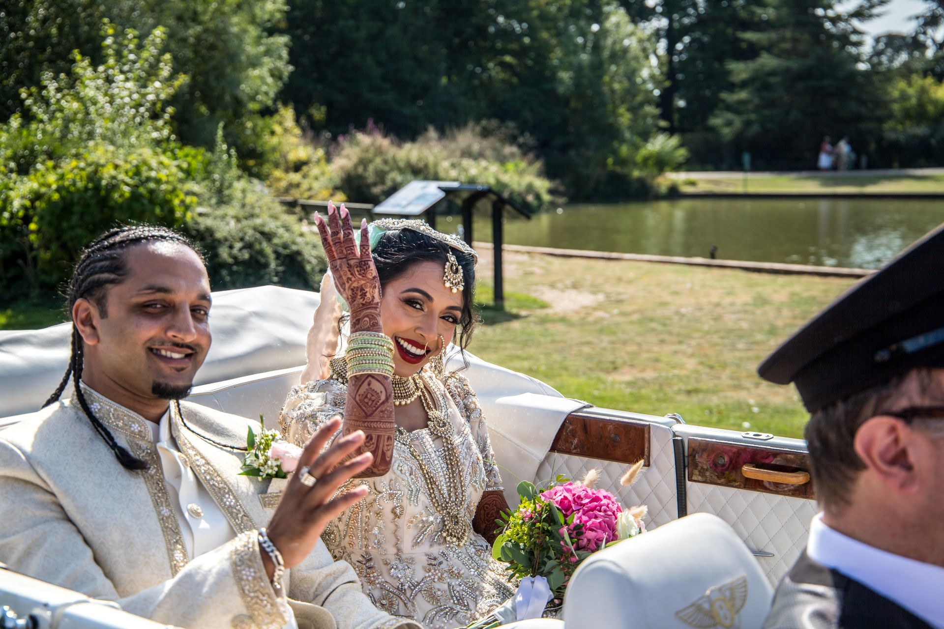 Indian bride seated in embroided bridal gown Lehenga dress seated and waving from an open-top car