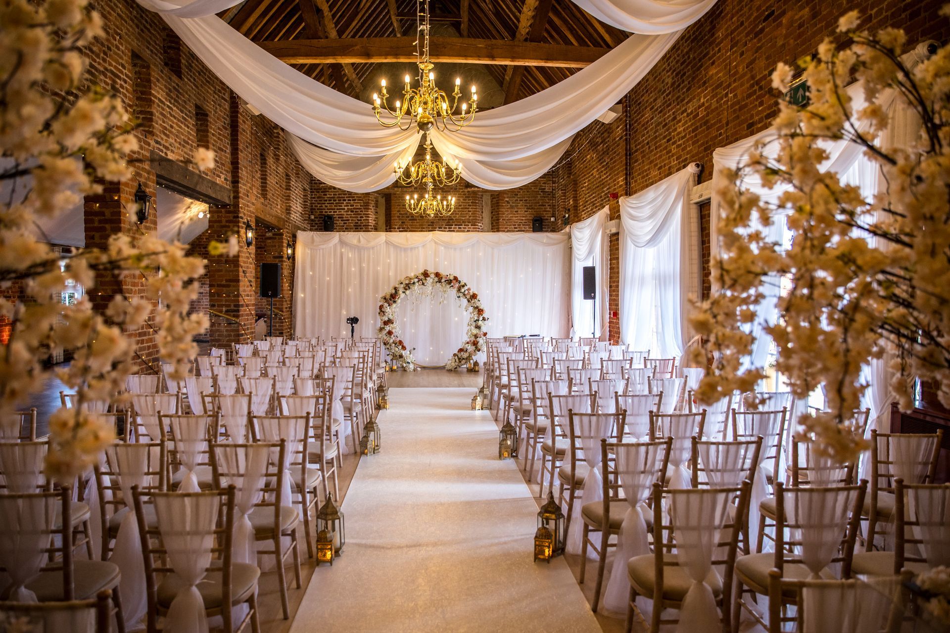 Wedding ceremony decor Forty Hall with floral arch as ceremony backdrop and a cream chairs with a white sash