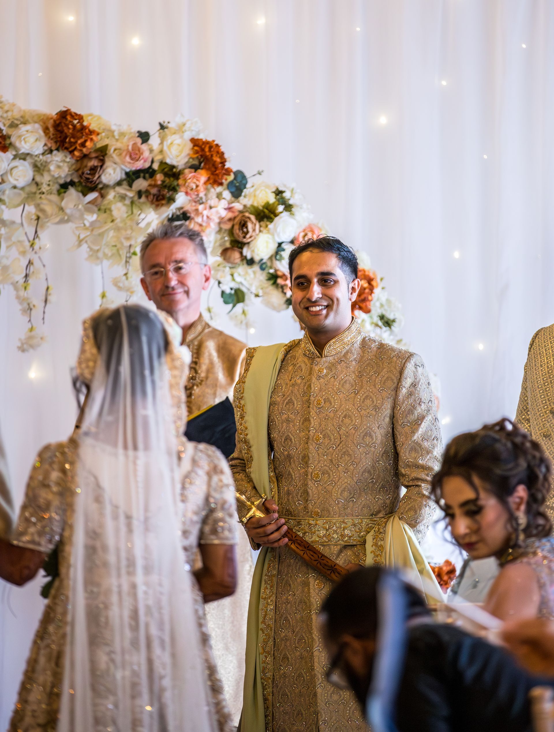 Indian groom in traditional dress looking at this bride as she walks down the aisle
