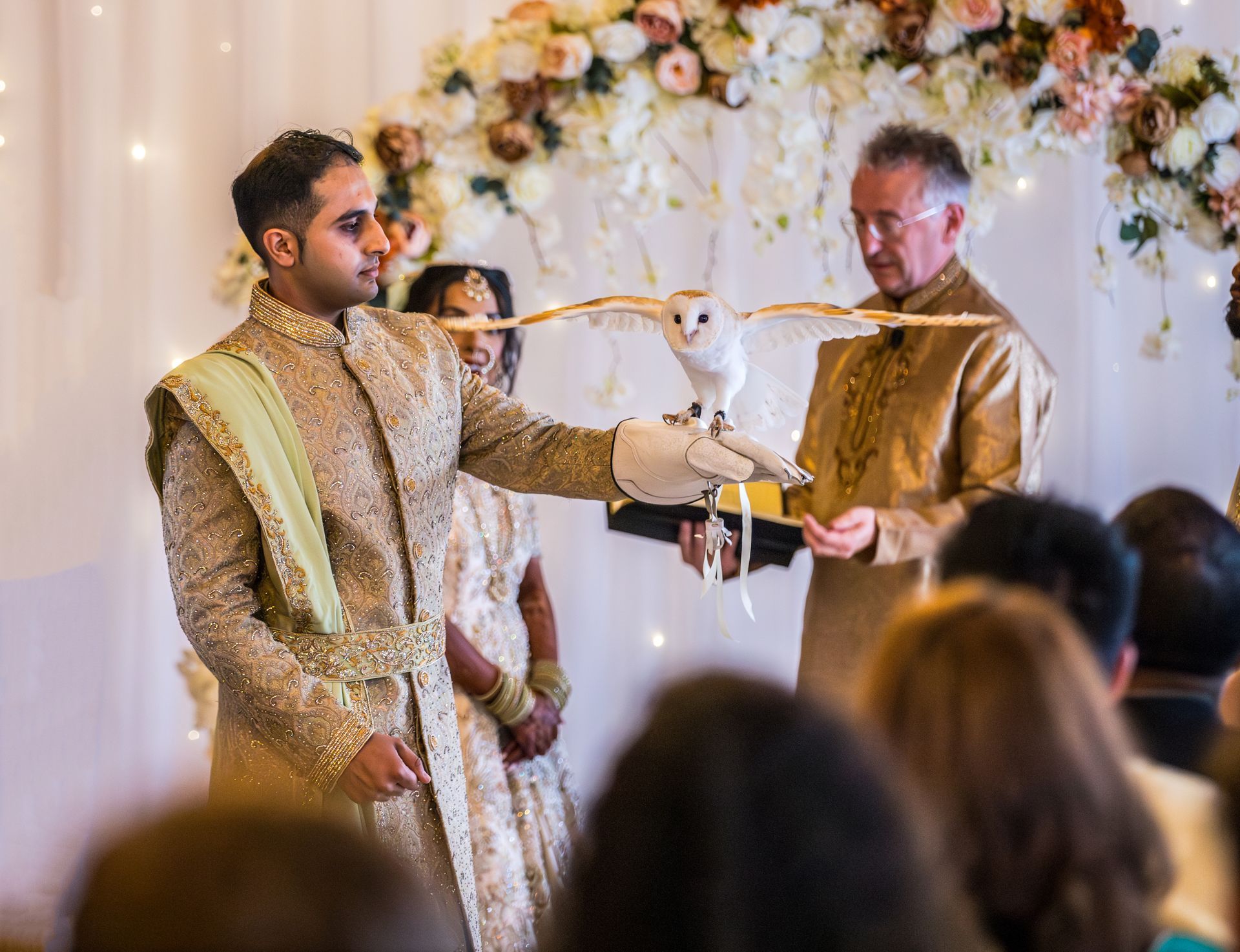 Indian groom with arch outstretched holding a white owl wing wings outstretched