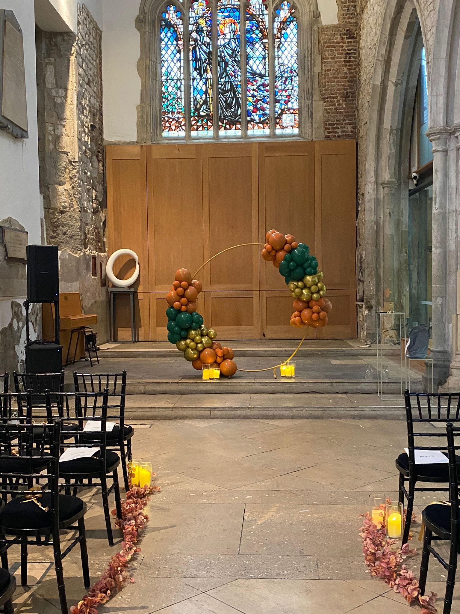 Colourful wedding ceremony orange green balloons on a hoop at St Ethelburgas London