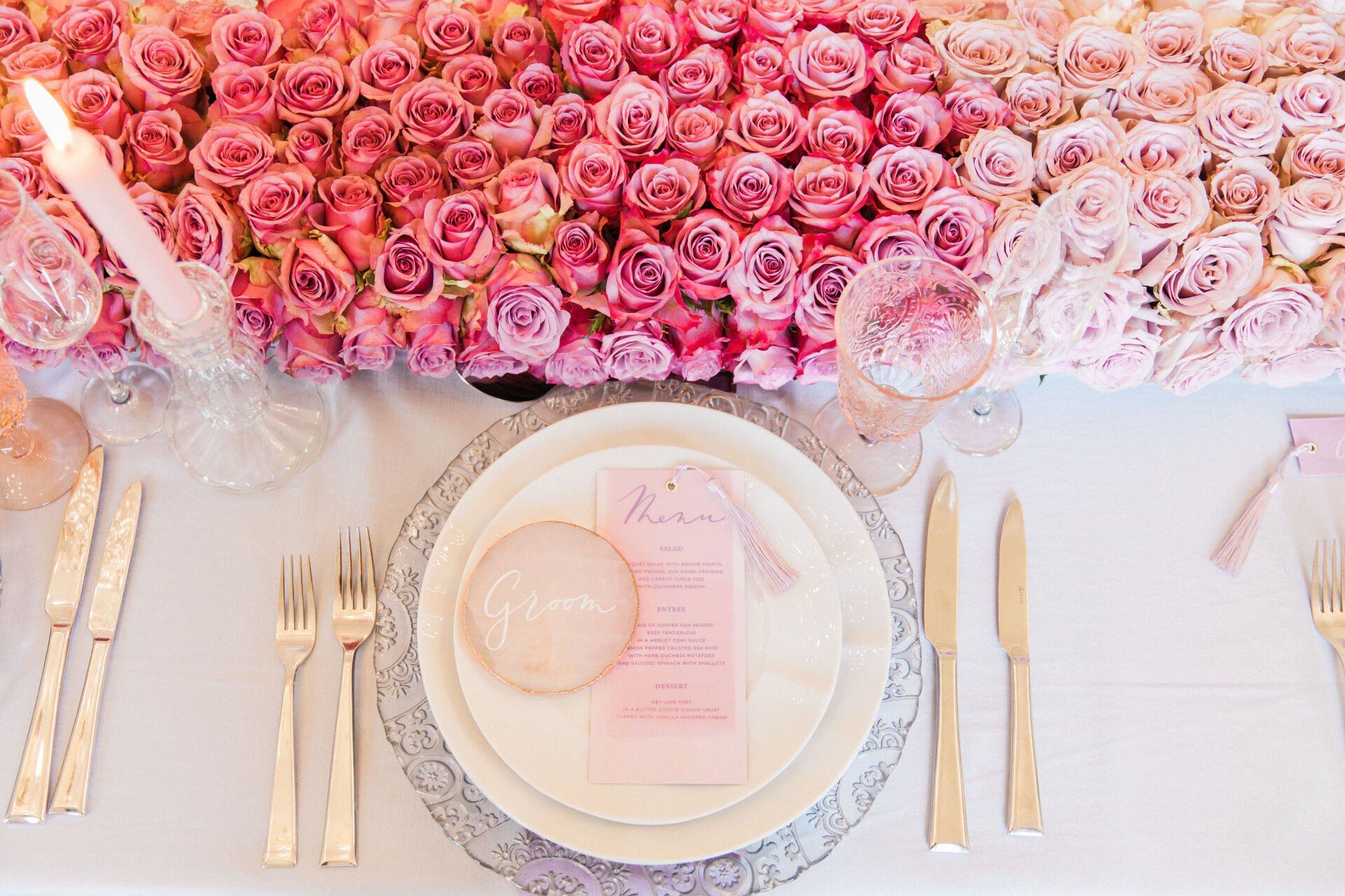 Picture of pink and white rose flower runner on a table with a glass charger plate and pink menu creative design by Pearline Events