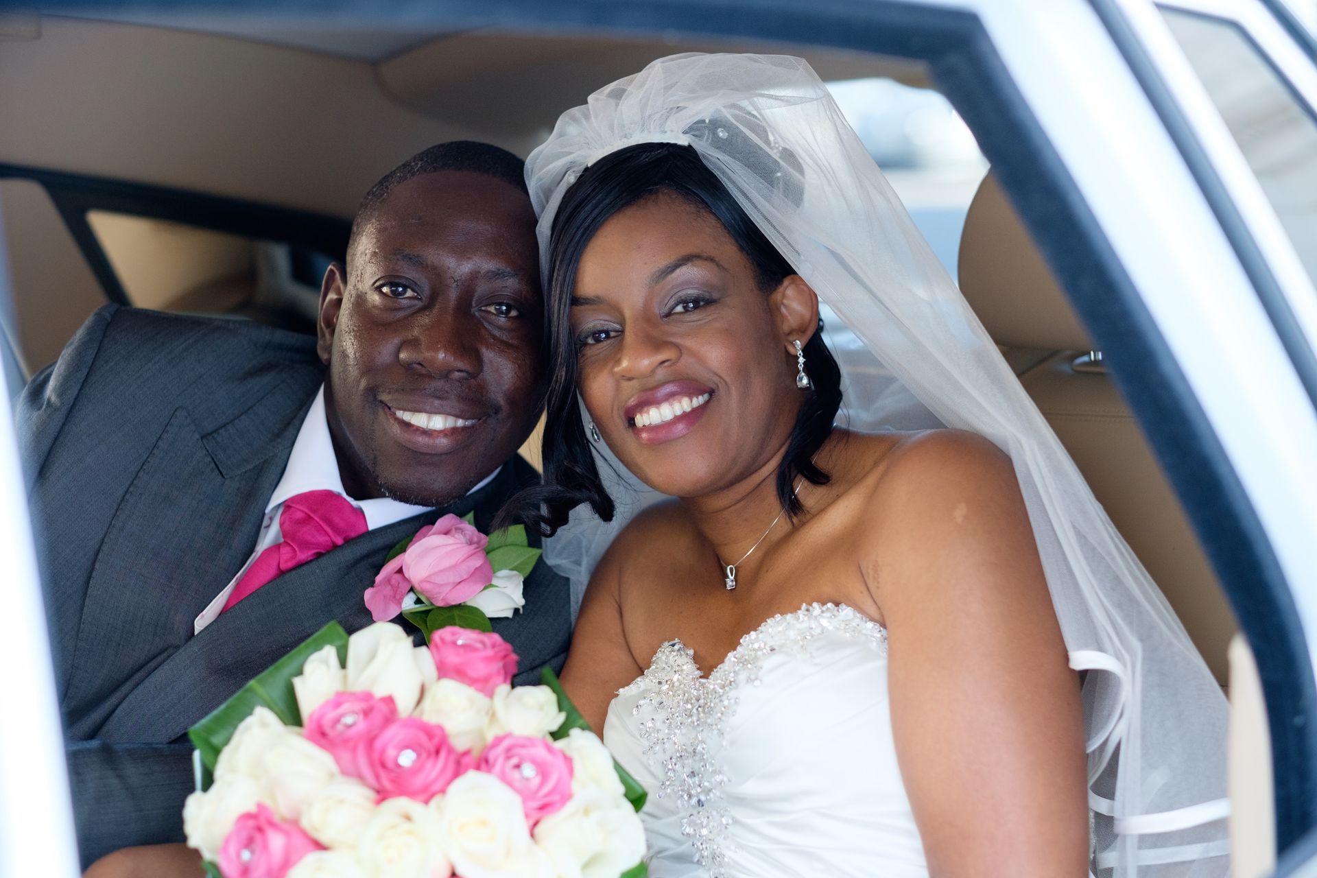 Black mans hand and mixed raced females hand with diamond engagement ring on holding each others little finger as they walk