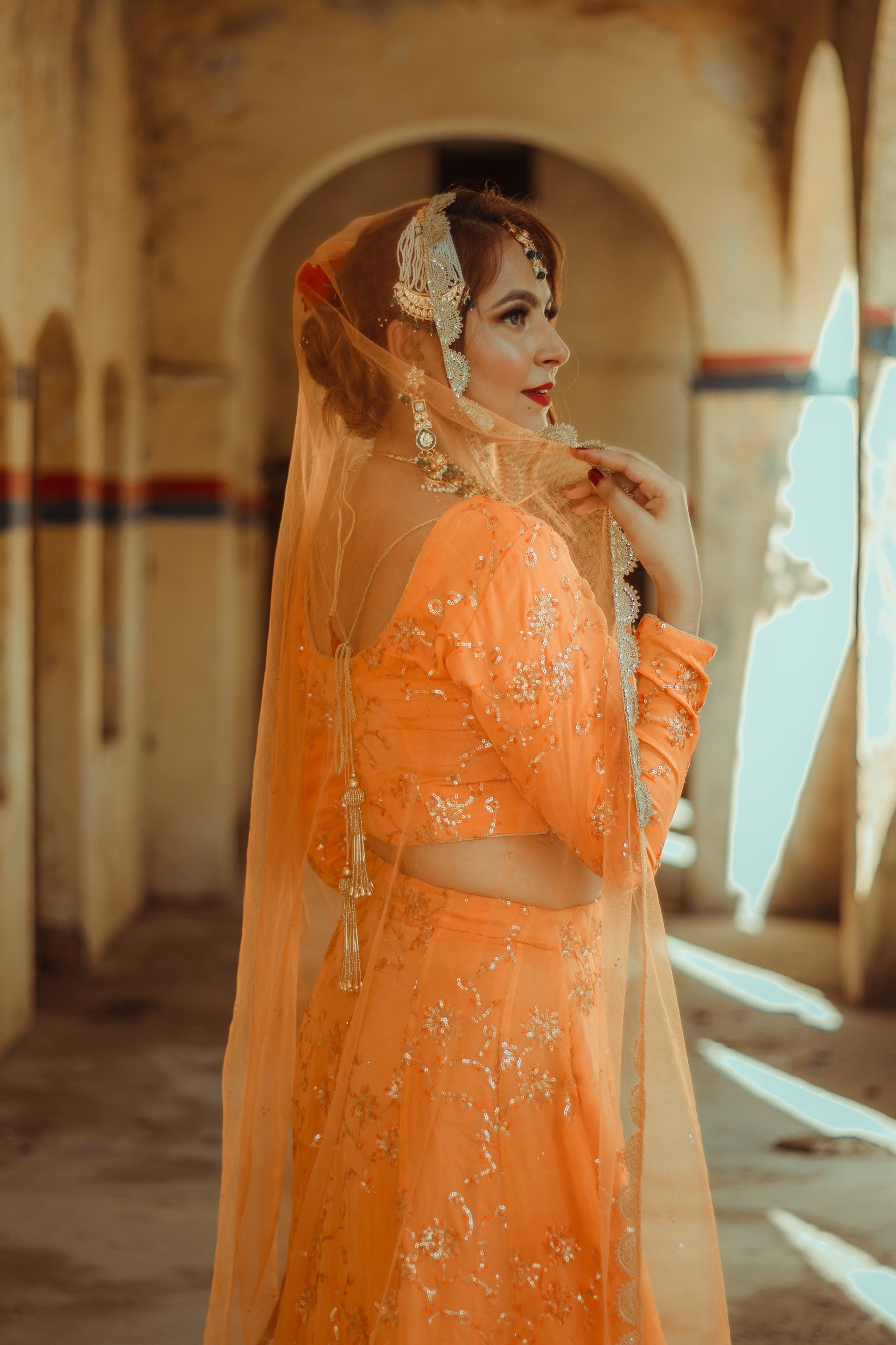 Asian woman in orange and gold sari looking out
