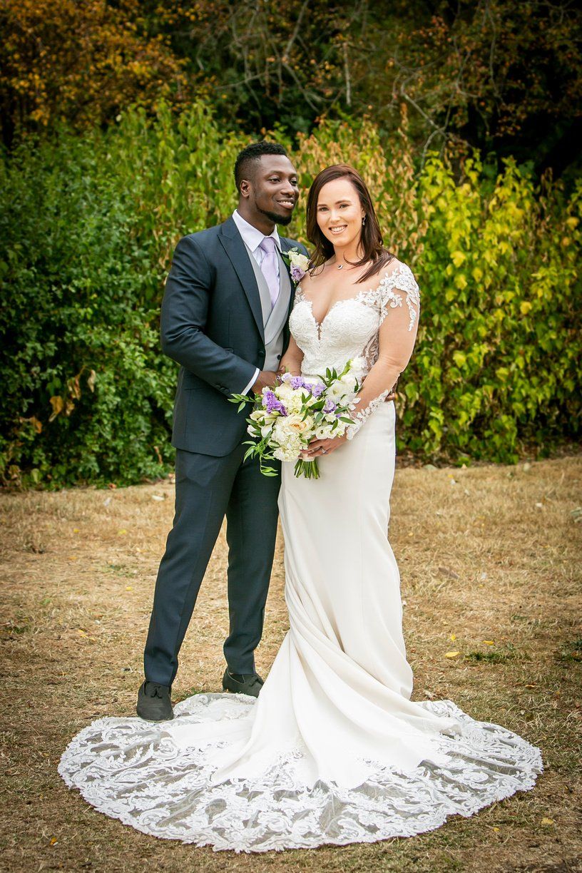 Black groom white bride holding bouquet standing outside forty hall