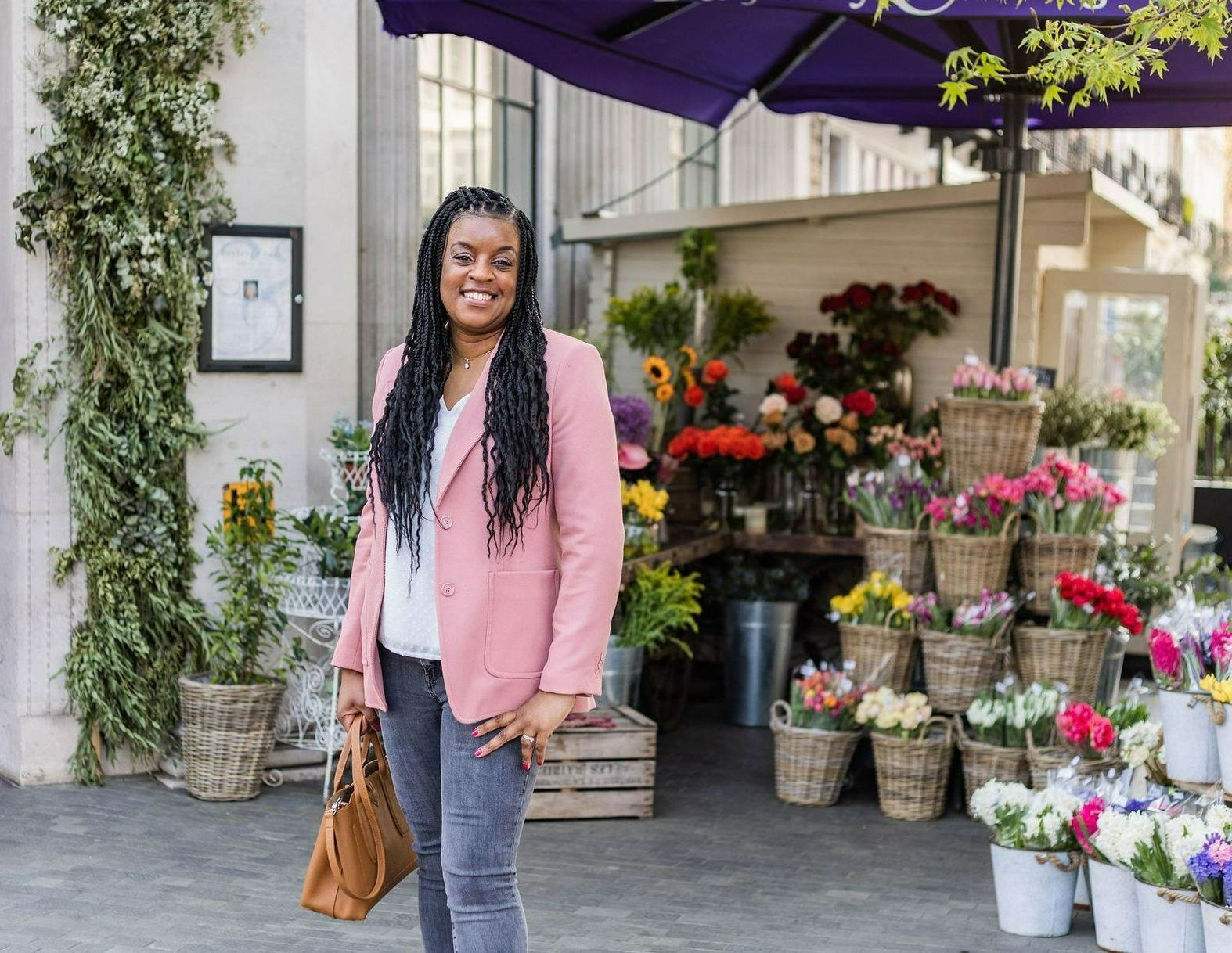 Natasha Pearline founder of Pearline Events in a peach jacket standing and smiling outside a London florist