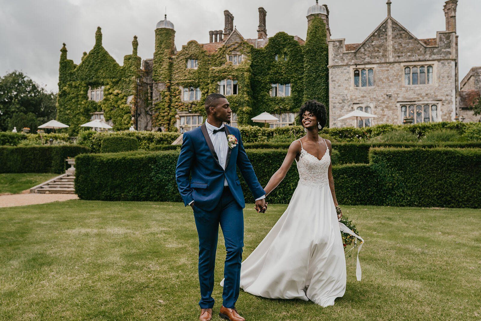 Black bride and groom holding hands and walking outside Eastwell Manor