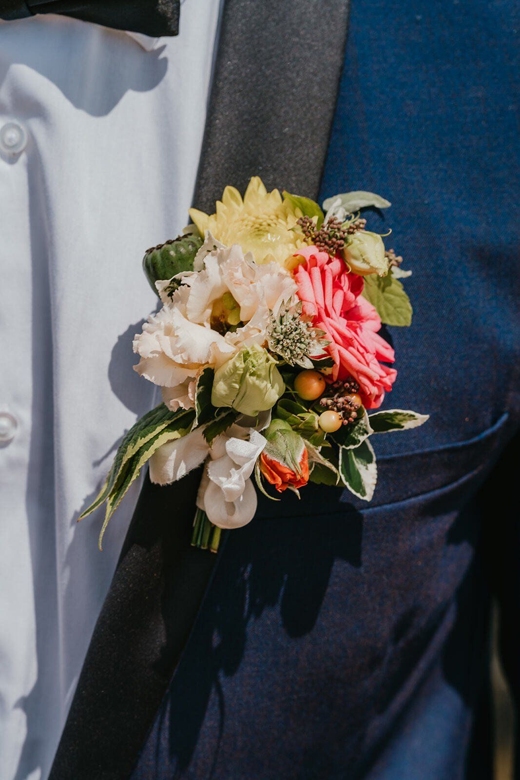 Grooms wearing blue jacket with peach and cream floral buttonhole,