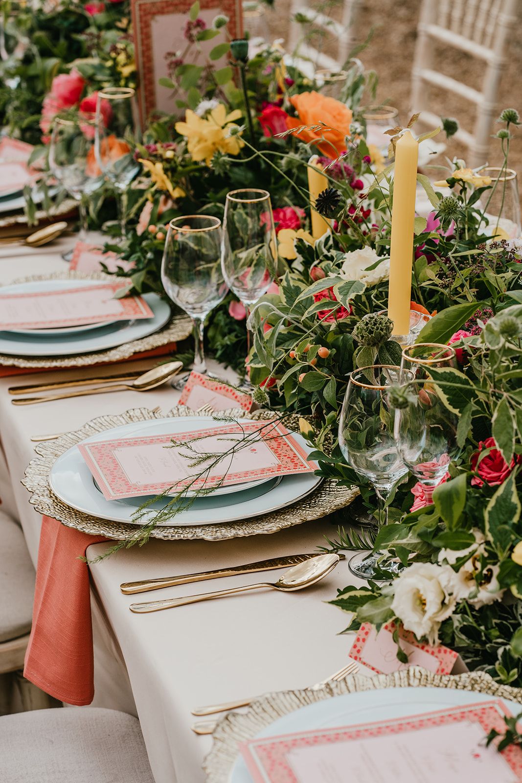 Wedding table set up with floral table runner, gold charger plates and peach napkins