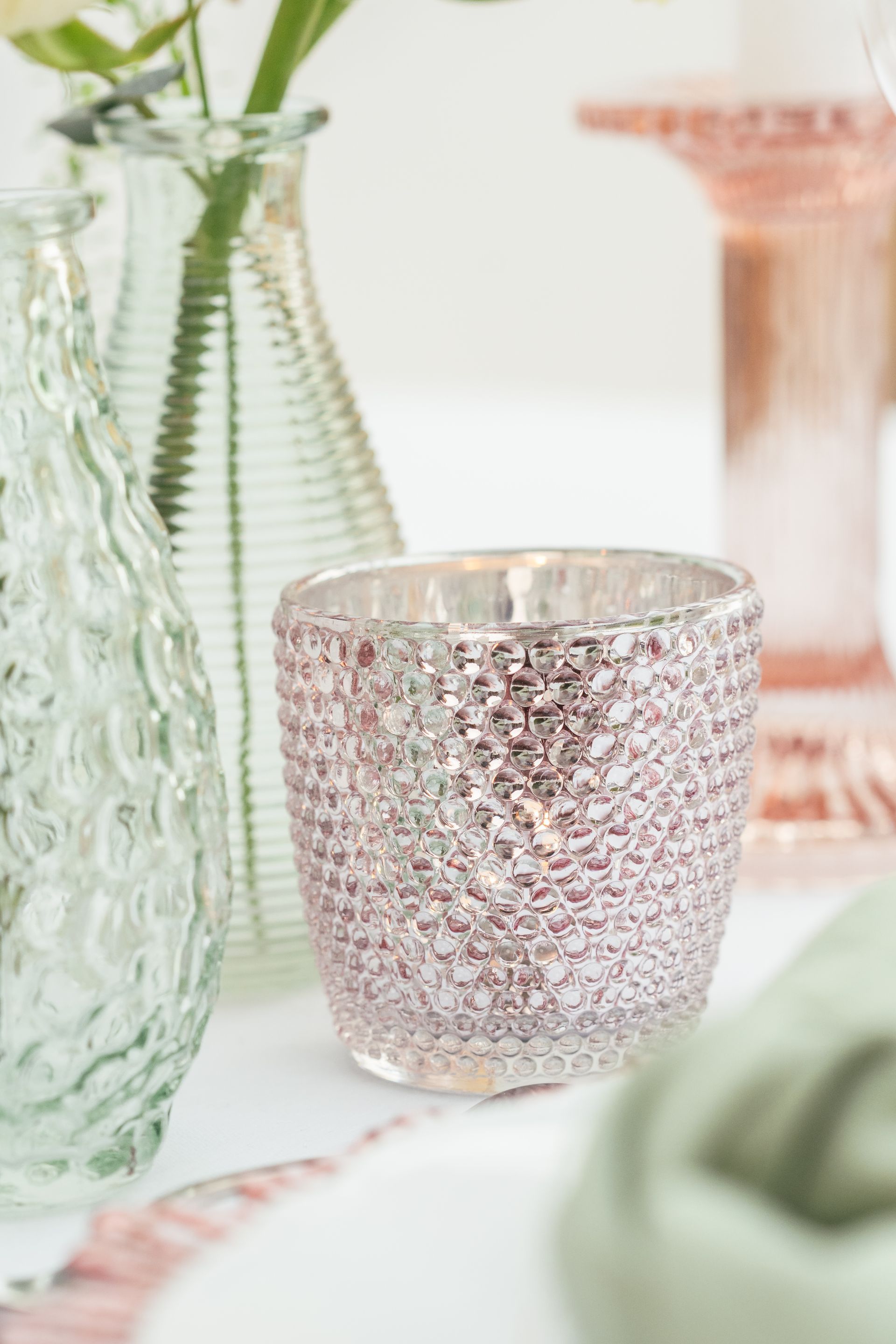 Pink tea light holder displayed on table with pink charger plate and vases