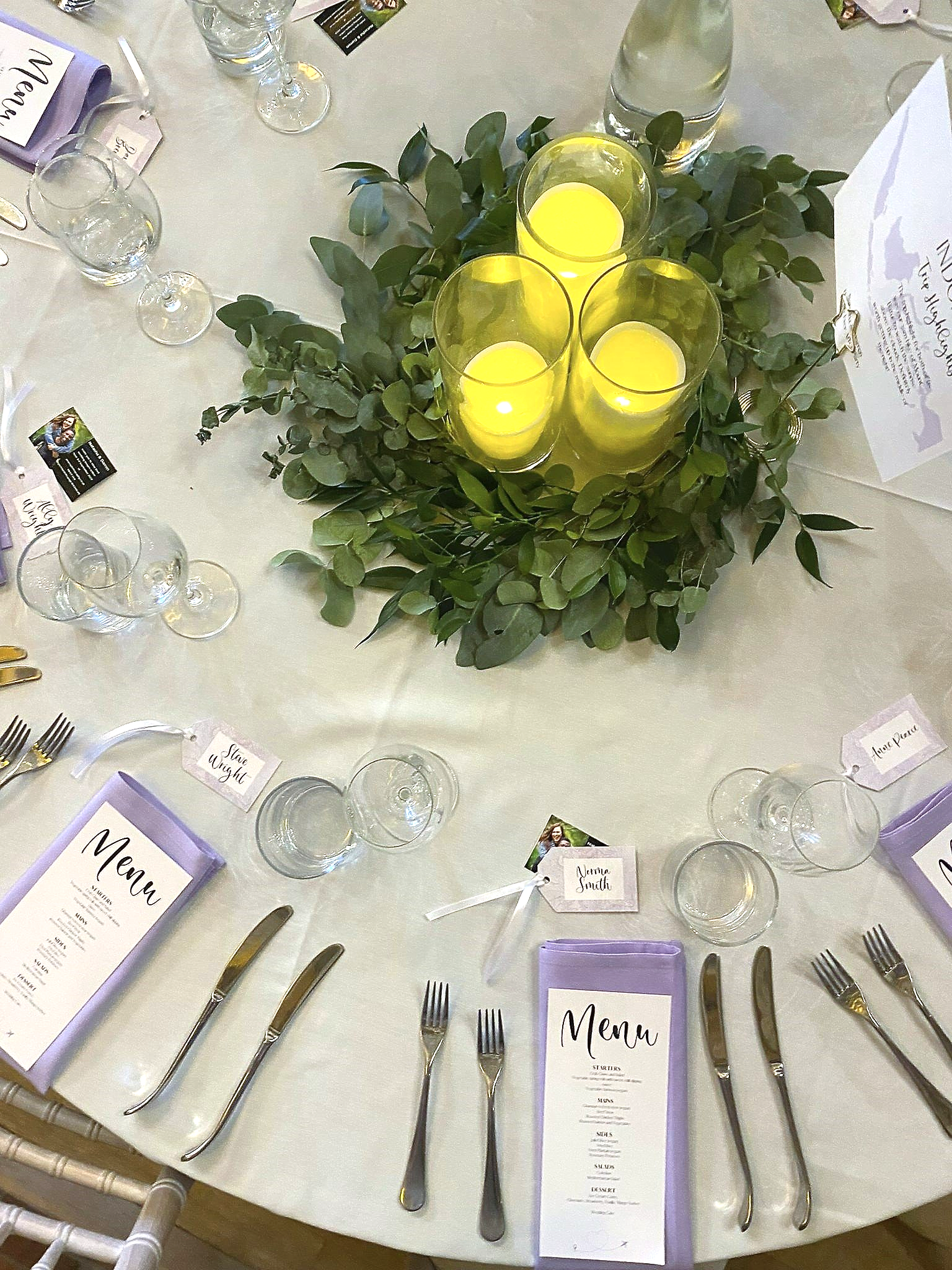 aerial view of a round wedding reception table with lilac napkins and pillar candle centrepieces
