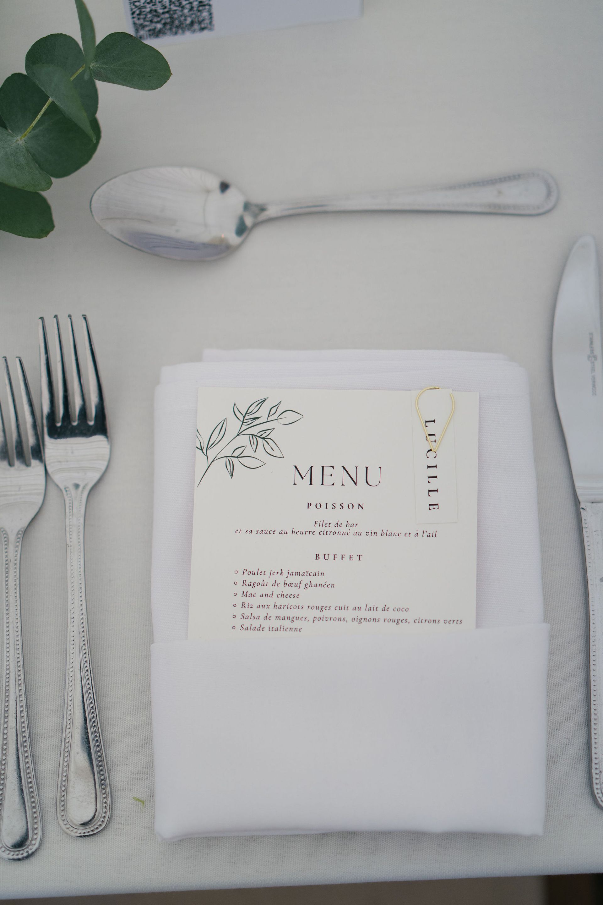 Wedding menu in French on white paper a white napkin and silver cutlery beside it