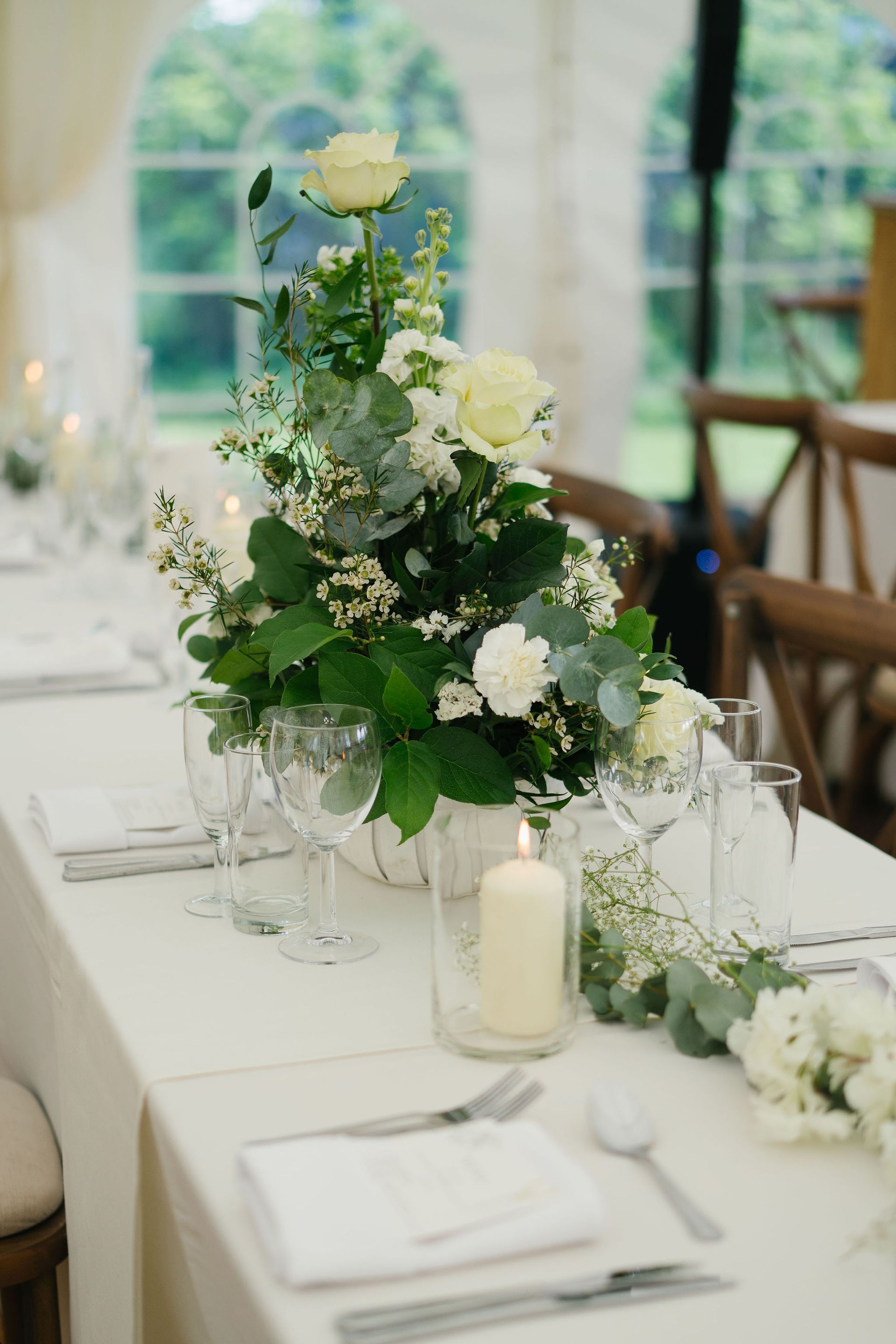 marquee wedding reception long table set up with candles in vases fresh white flowers