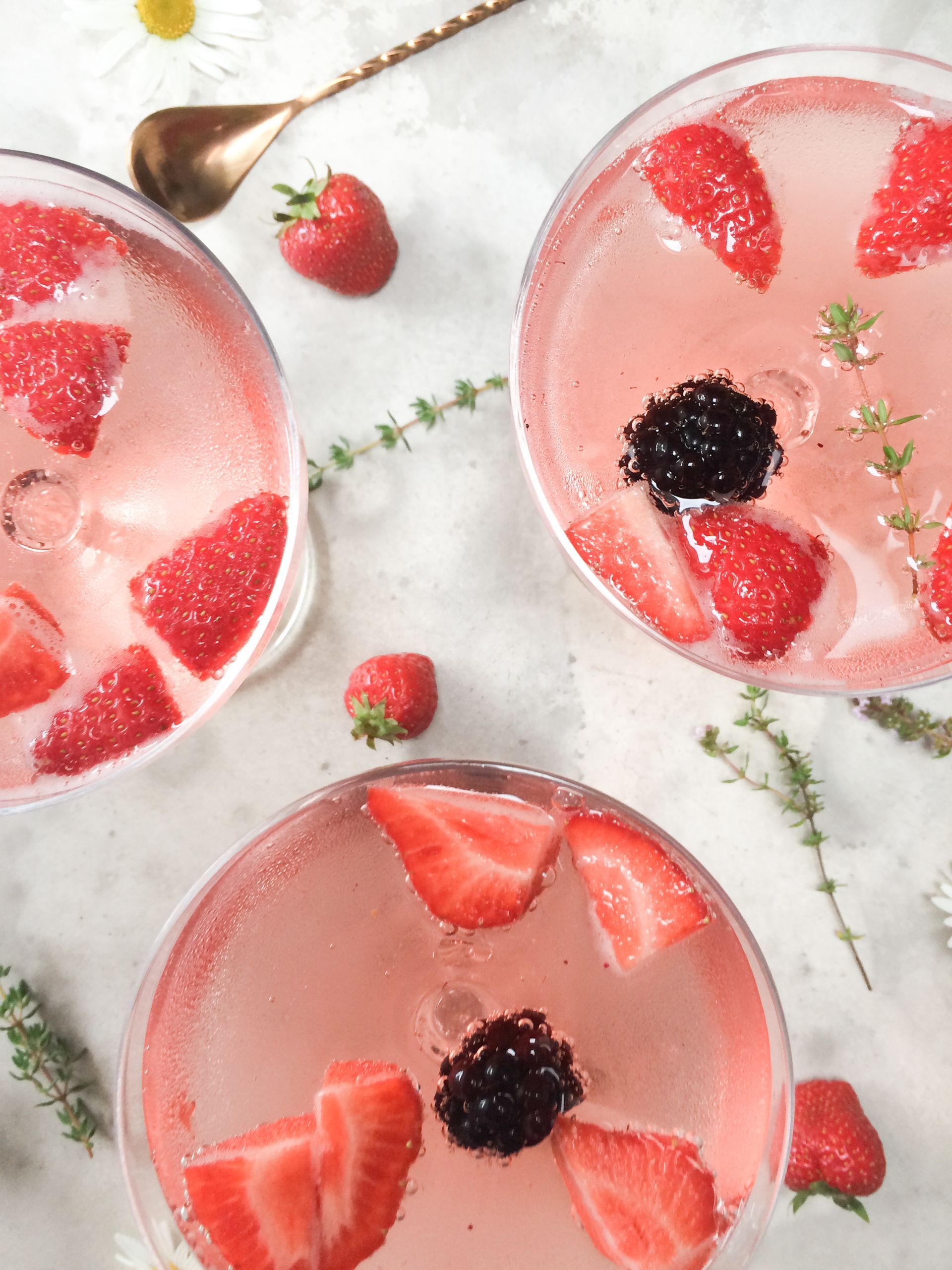 Red cocktails with strawberry and blackberry garnish